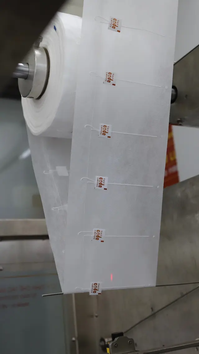 A roll of steeped-bag film with custom brand tags on the packing machine