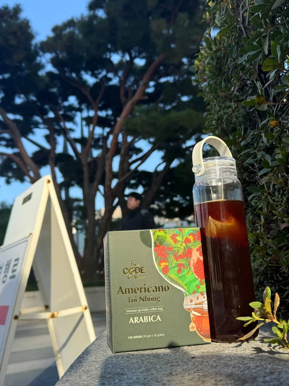 The Code Coffee Americano steeped bag box beside a bottle of iced coffee