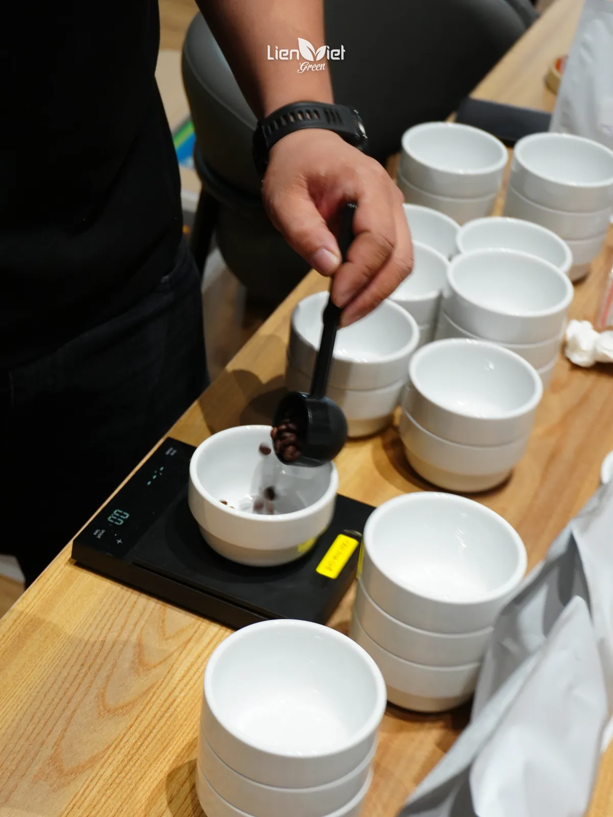 Barista Liên Việt Green cân hạt rang vào chén cupping để đánh giá hồ sơ rang, tại Flow & Brew #01