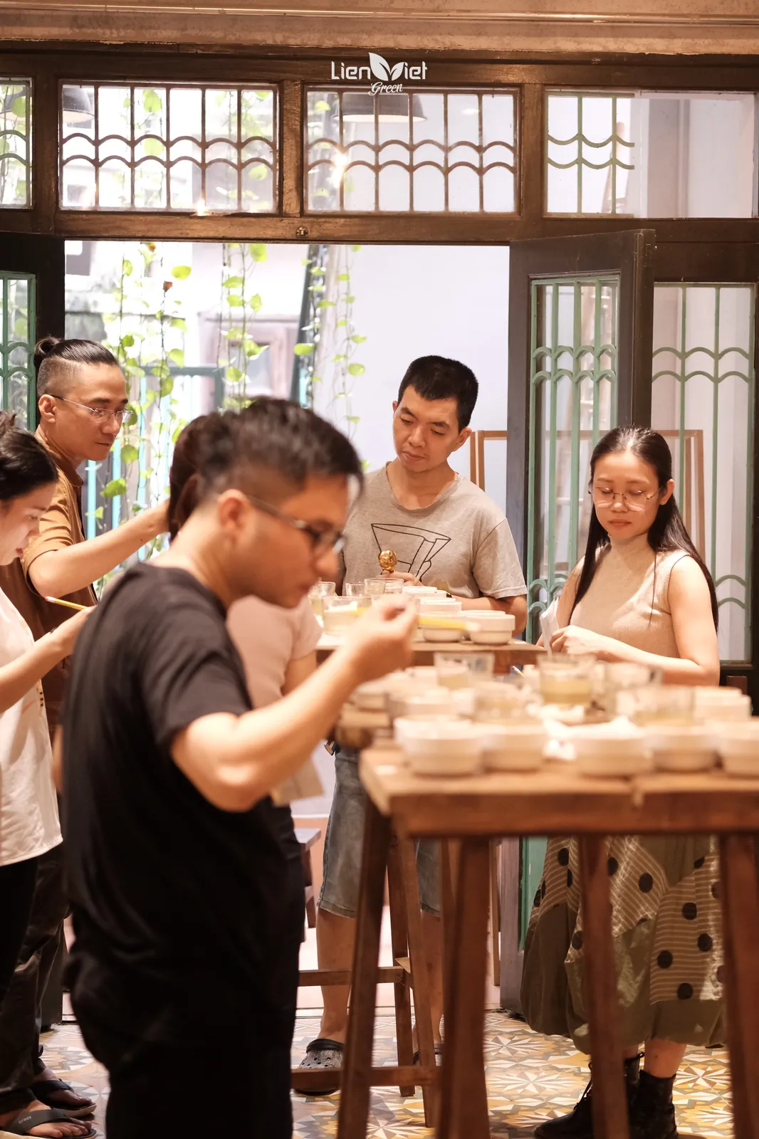 Nhóm chuyên gia nếm các chén mẫu quanh bàn gỗ trong buổi cupping Fine Robusta