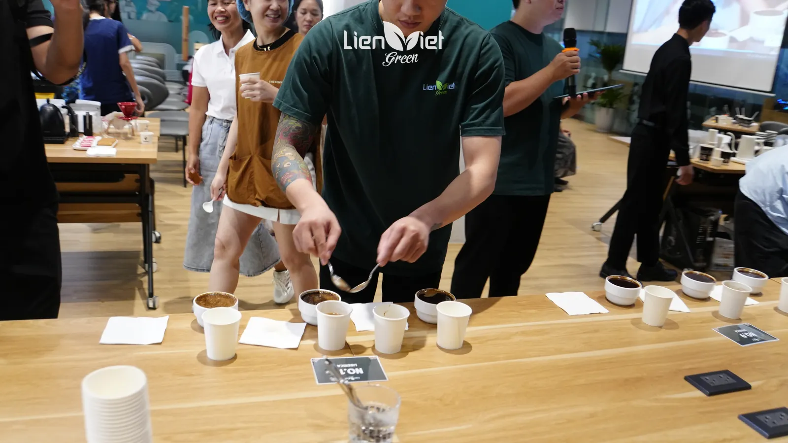 Nhân viên Liên Việt Green phá lớp bột (break crust) trên chén cupping theo quy trình thử nếm, tại sự kiện The New Crop – Trải nghiệm mùa vụ mới