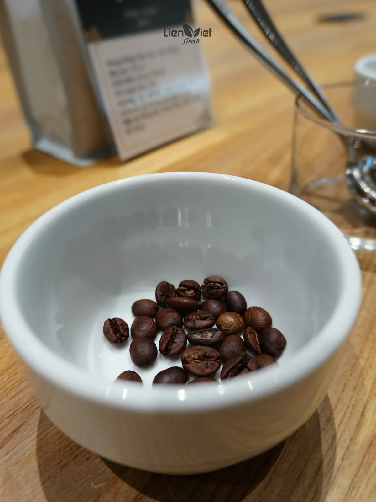 Cận cảnh hạt cà phê rang nâu bóng trong chén cupping sứ trắng