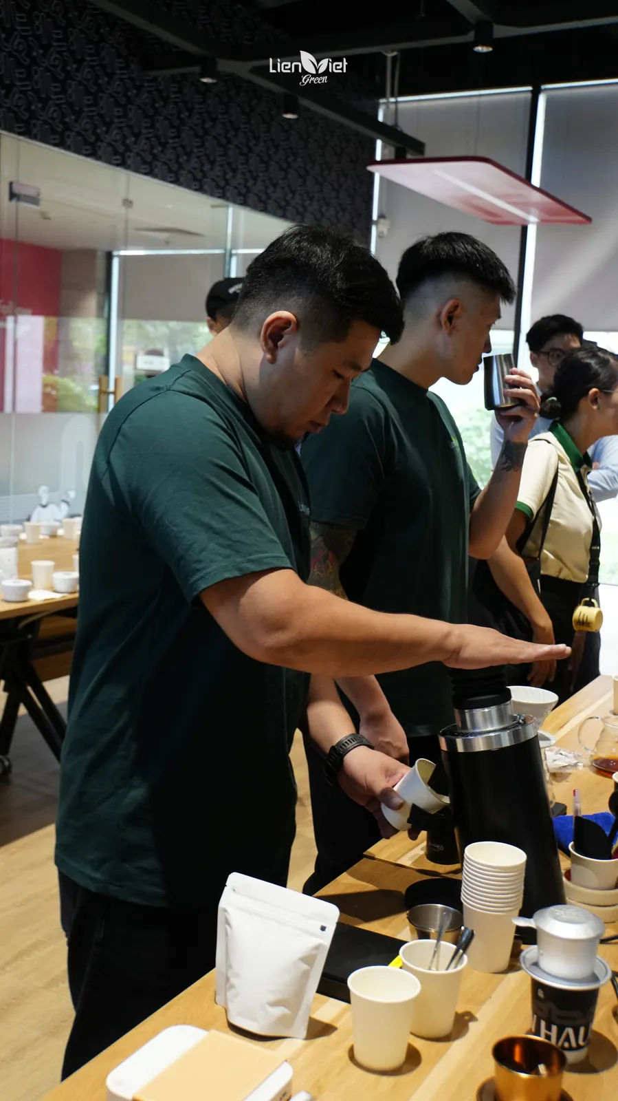 Lien Viet Green team grinding and brewing coffee samples at a long table