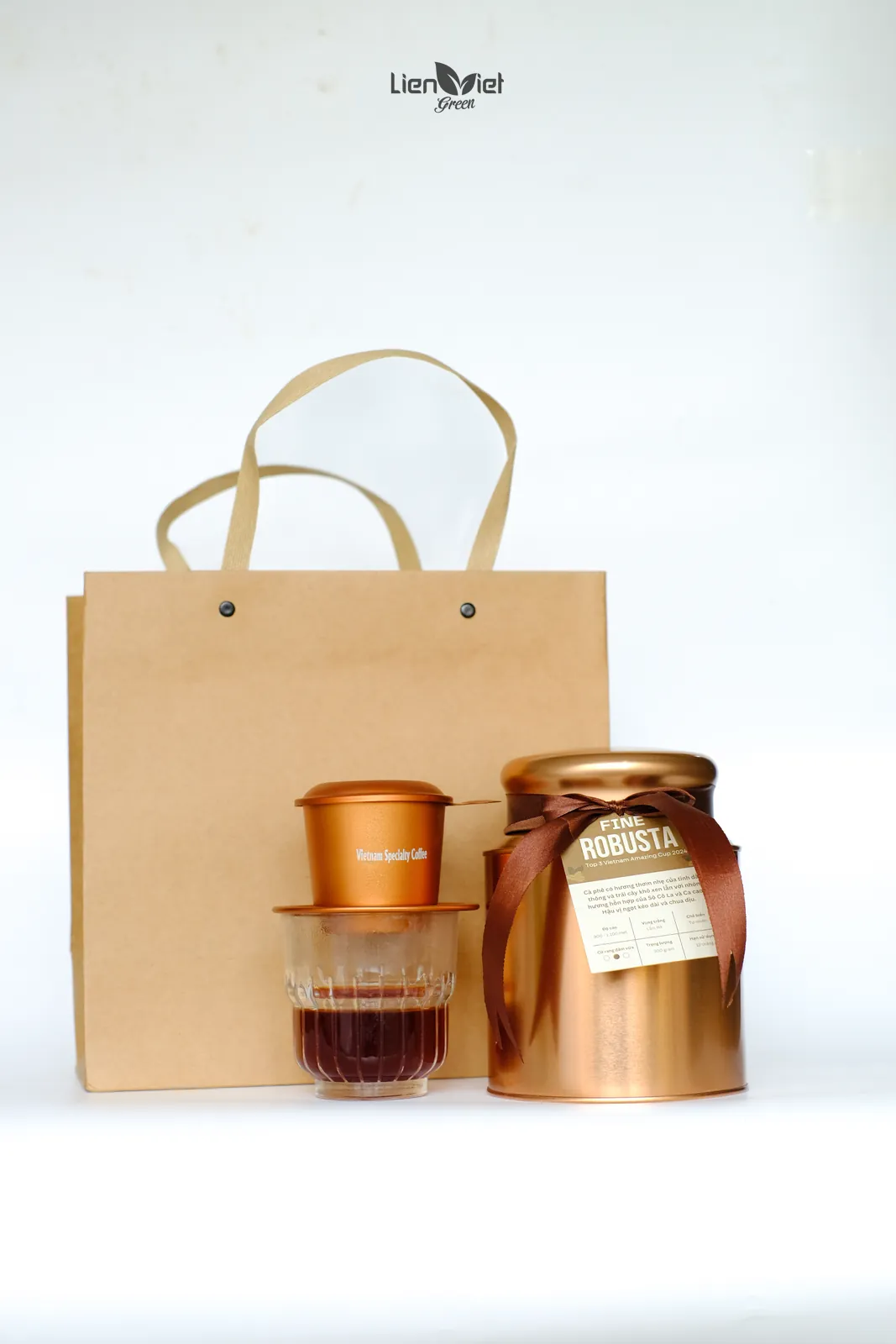 Set quà cà phê đóng gói riêng gồm phin đồng, ly thuỷ tinh và hũ Robusta trước túi giấy kraft