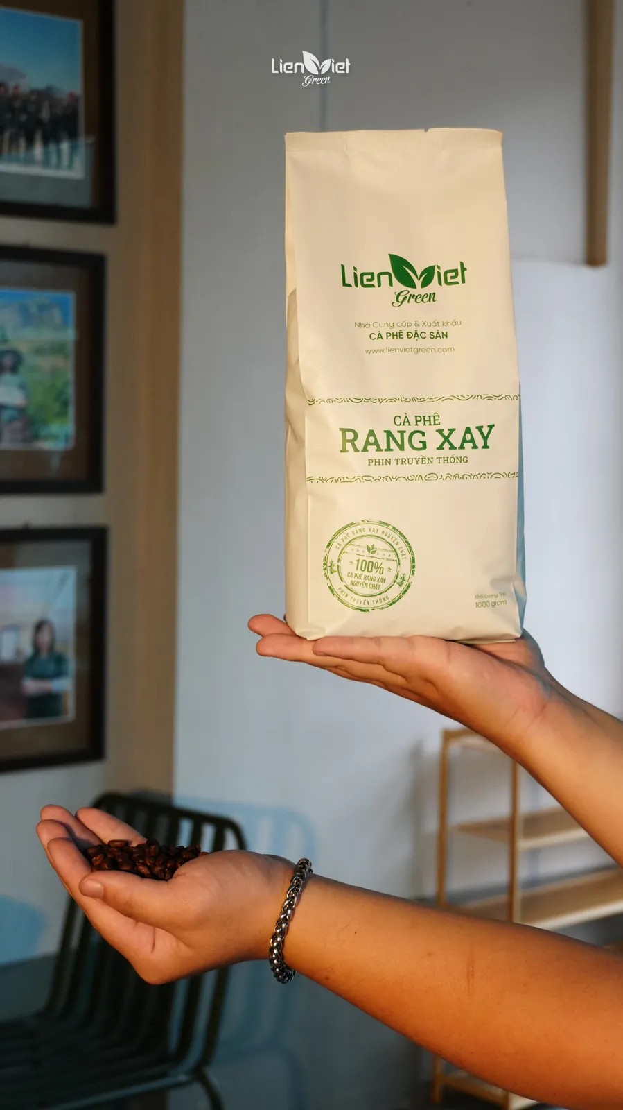Bàn tay nâng túi cà phê rang xay Liên Việt Green, tay kia cầm nắm hạt rang