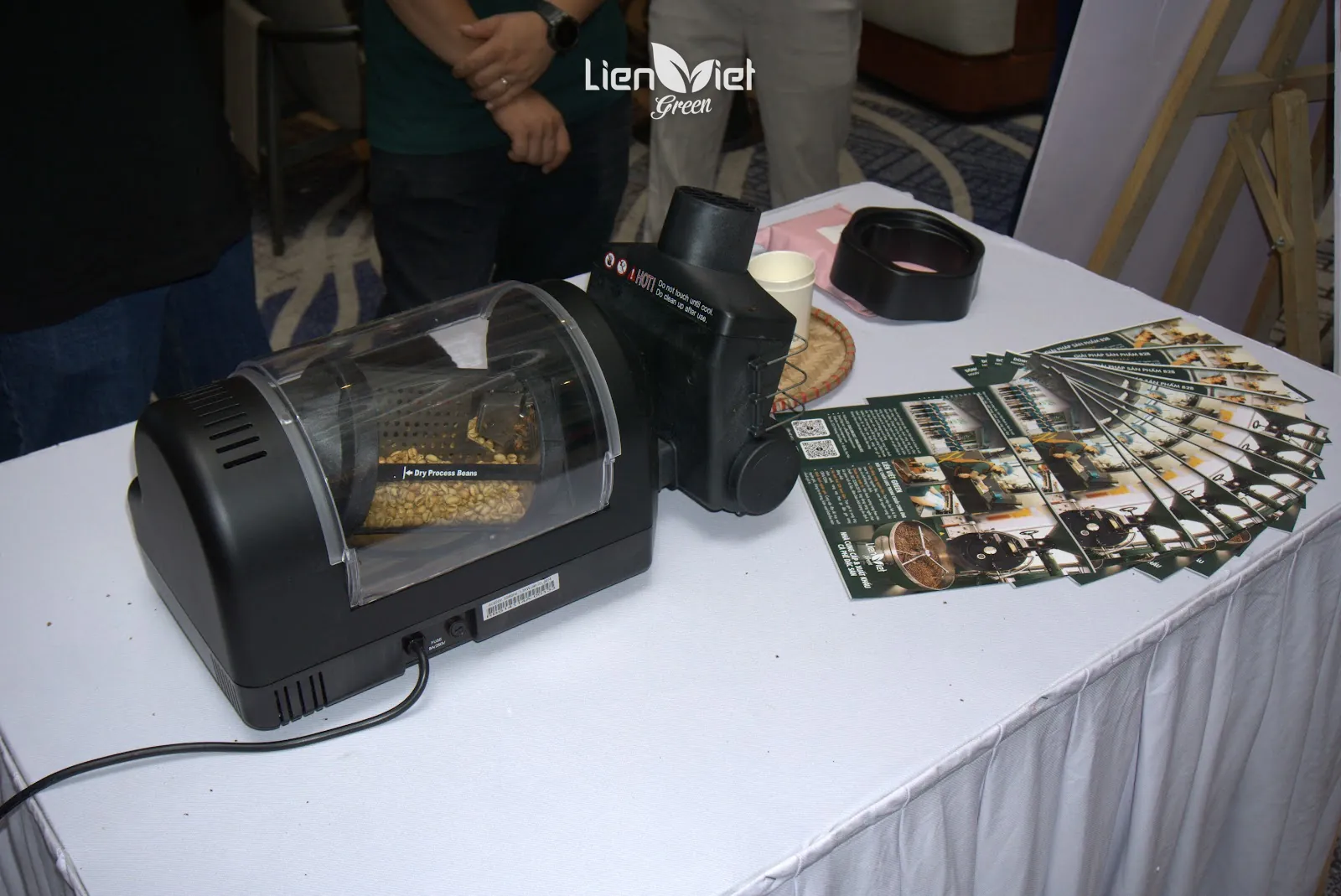 Mini roaster with green beans beside a stack of Lien Viet Green B2B brochures