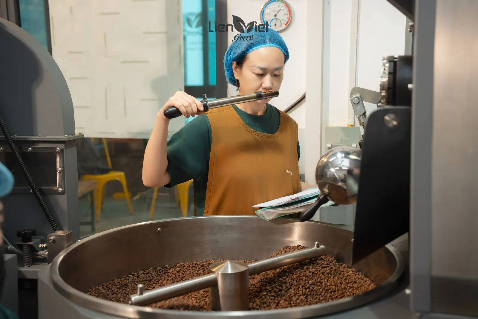Roaster pulling a bean sample to smell beside the roaster
